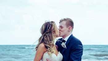 man and woman kissing each other near on body of water