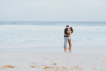man and woman kissing each other on the seashore