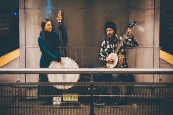 man and woman playing string instruments standing near wall