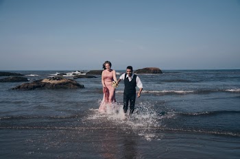 Man and woman running on seashore while holding hands