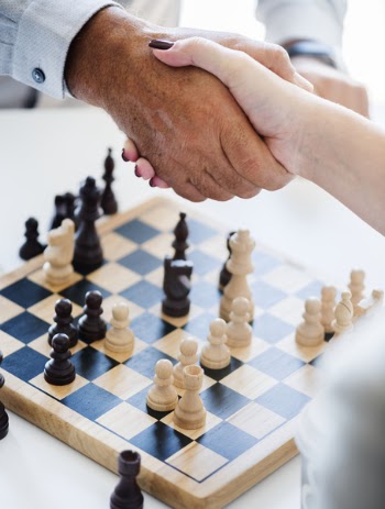 Man and Woman Shaking Hands over a Game of Chess