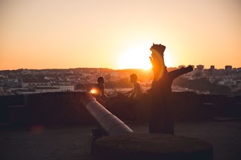 man and woman sitting and facing near concrete fence during golden hour