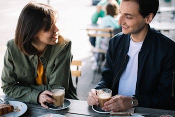 Man and Woman Sitting at Table Holding Drinking Glasses
