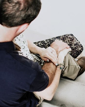 man and woman sitting beside each other holding hands