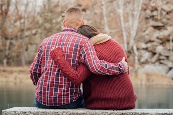man and woman sitting near lake