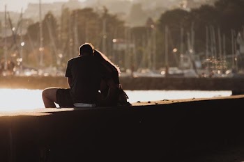 man and woman sitting on bay near body of water during daytime