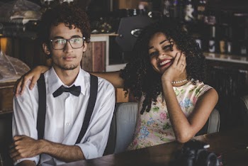 Man and Woman Sitting on Chair Beside Table