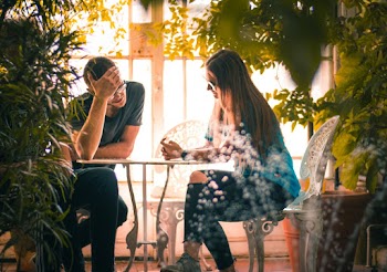 Man and Woman Sitting on Chairs Beside a Table 