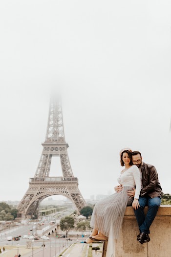 Man And Woman Sitting On Concrete Wall Near Eiffel Tower