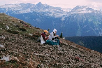 man and woman sitting on ground looking at mountain