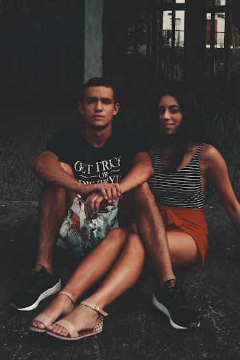 Man and Woman Sitting on Pavement