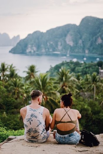 man and woman sitting on rock near jungle