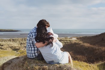 Man and Woman Sitting on Stone Carrying Baby