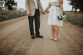 man and woman standing at middle of road beside trees