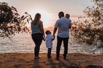 Man and Woman Standing Beside Body of Water during Sunset