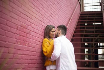 Man and Woman Standing Beside Red Brick Wall About to Kiss