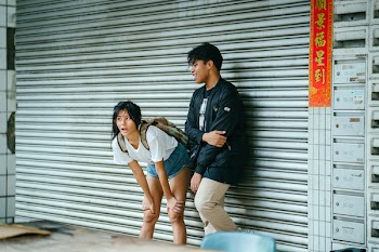 Man And Woman Standing In Front Of Metal Roll-up Door