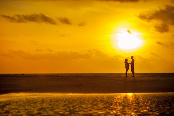 Man and Woman Standing Near Seashore Under Sunset