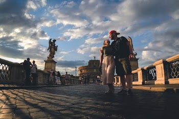Man and Woman Standing Near Statue Under Cloudy Sky during Daytime