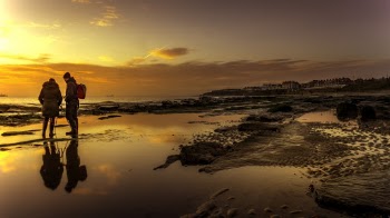 Man and Woman Standing on Body of Water during Sunset
