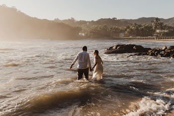 Man and Woman Standing on Body of Water Near Rock Formation