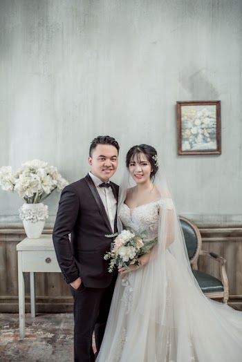 Man and Woman Taking Wedding Photo Inside Gray Concrete House With Wall Arts and Flowers on Vase
