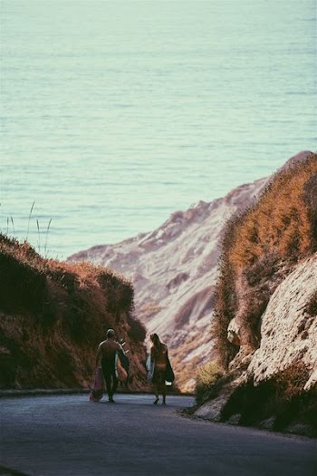 man and woman walking near rock formation