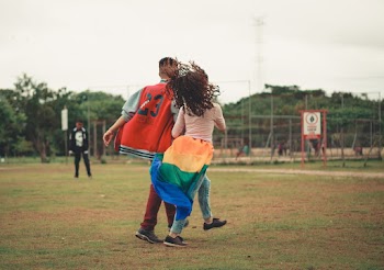 Man and Woman Walking on Green Grass Field