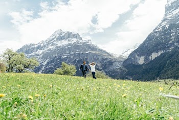 Man and Woman Walking on Meadow of Yellow Flowers