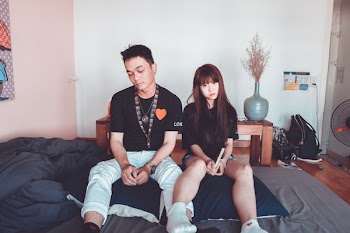 Man and Woman Wearing Black Shirts Sitting on Bed
