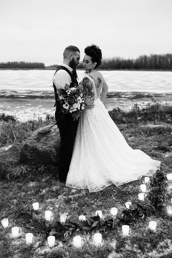 Man and Woman Wearing Wedding Dresses Standing Near Body of Water Surrounded by Pillar Candles in Grayscale Photo