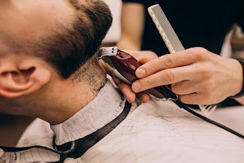 Man at a barbershop salon doing haircut and beard trim Free Photo