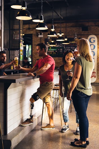 Man Being Served Beer Next to Two Conversing Women
