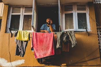 Man By An Open Window With Assorted Clothing Hanging On Clotheslines