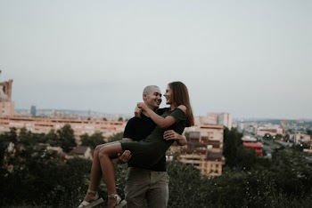 Man Carries Woman Near Green Plants Overlooking City