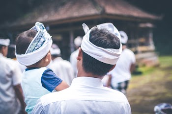 Man Carrying a Baby With White Headbands