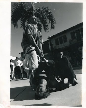 Man Carrying Another Man by Pulling His Belt