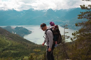 Man Carrying Baby Near Lake