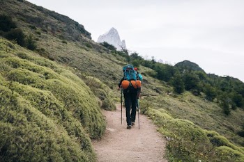 man carrying backpack and holding trike poles