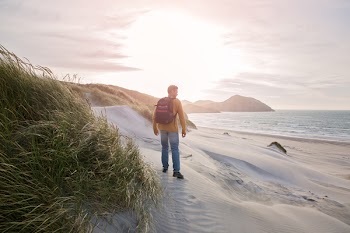 Man Carrying Black Backpack Standing on Seashore