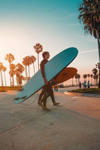 man carrying blue skateboard on park