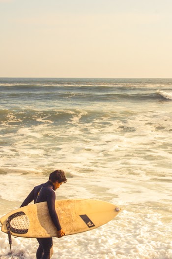 Man Carrying Surfboard Near Shoreline