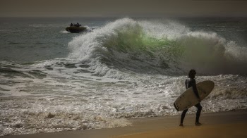 Man Carrying Surfboard on Seashore