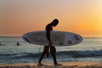 Man Carrying White Surfboard on Beach