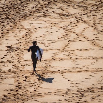 man carrying white surfboard standing on ground
