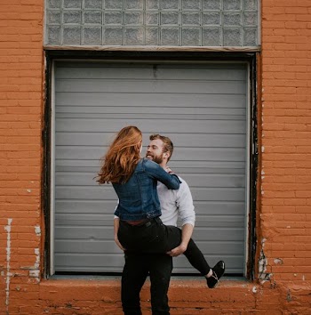 man carrying woman near shutter door
