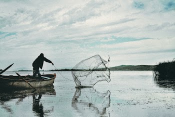 Man Casting His Net in the Body of Water