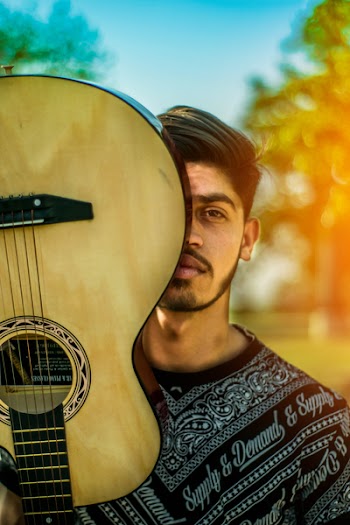 Man Covering Half of His Face by Guitar