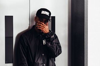 man covering his face in front of gray door