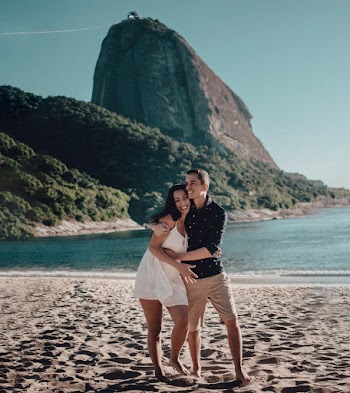 Man Cuddles Woman While Walking on Beach